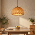 Handwoven bamboo rattan pendant lamp glowing above a wooden dining table