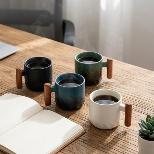 Retro ceramic coffee cup with wooden handle on a warm wooden desk beside a notebook